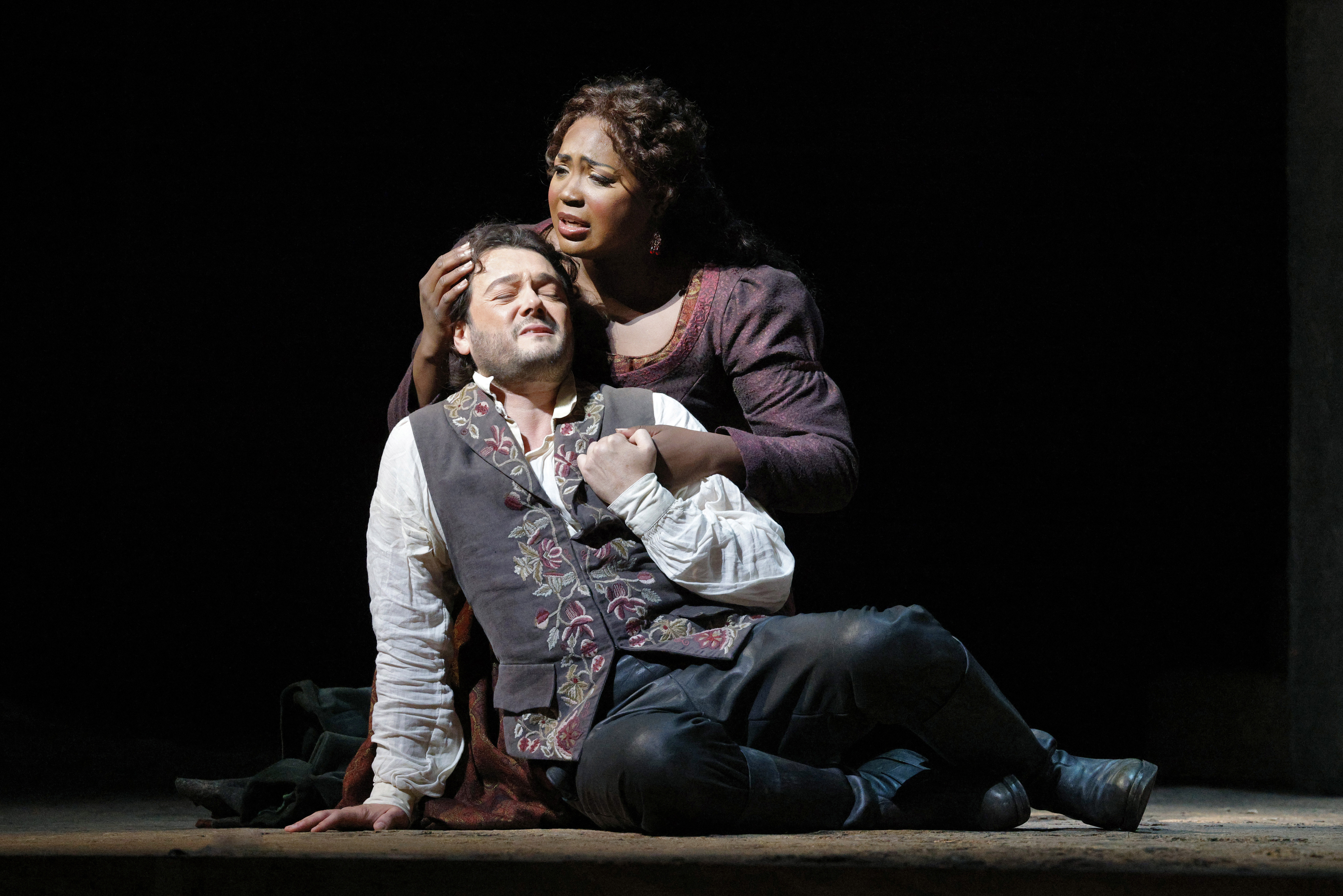 women singing while embracing man on stage