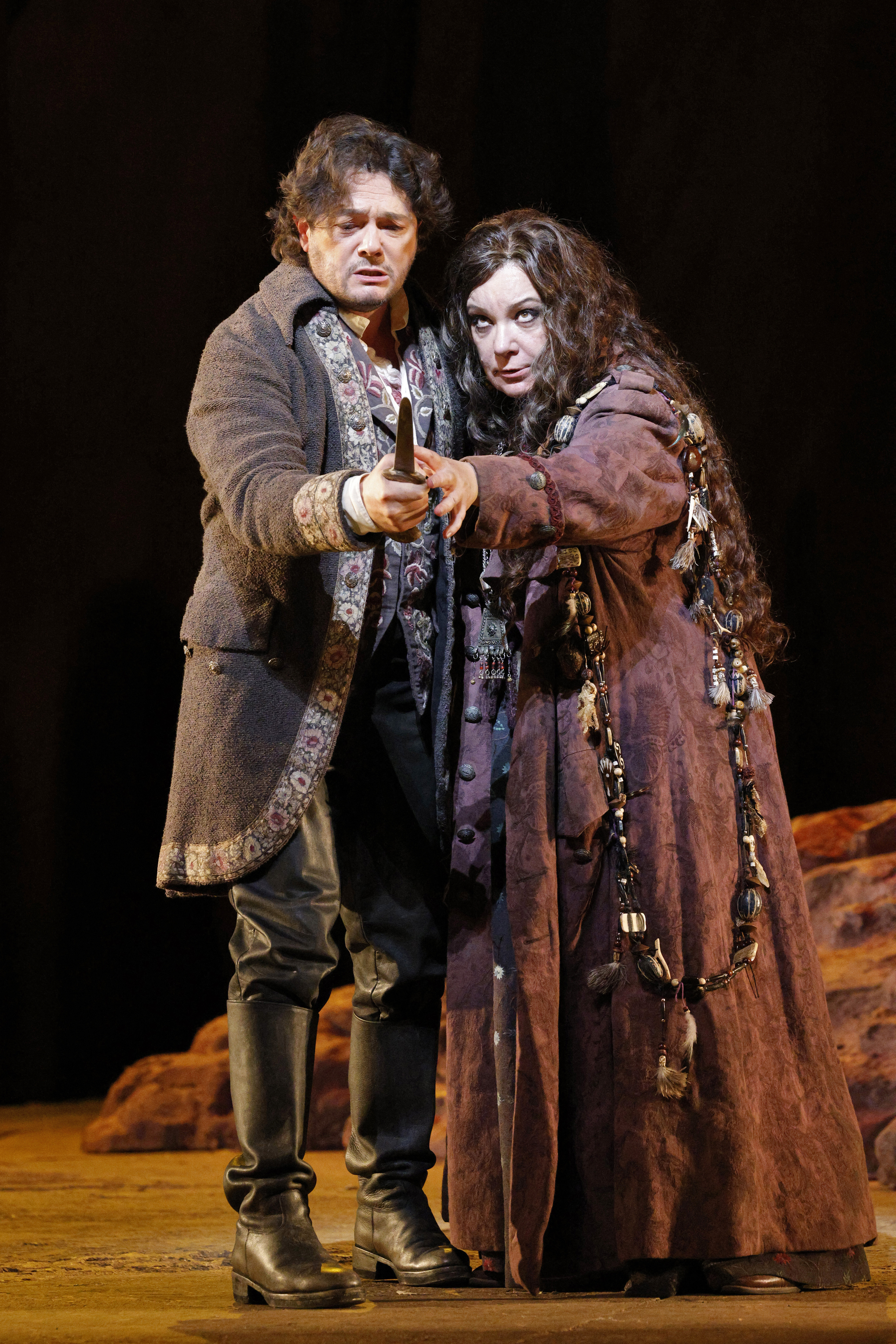 man and woman embracing eachother singing with a knife pointed towards the audience
