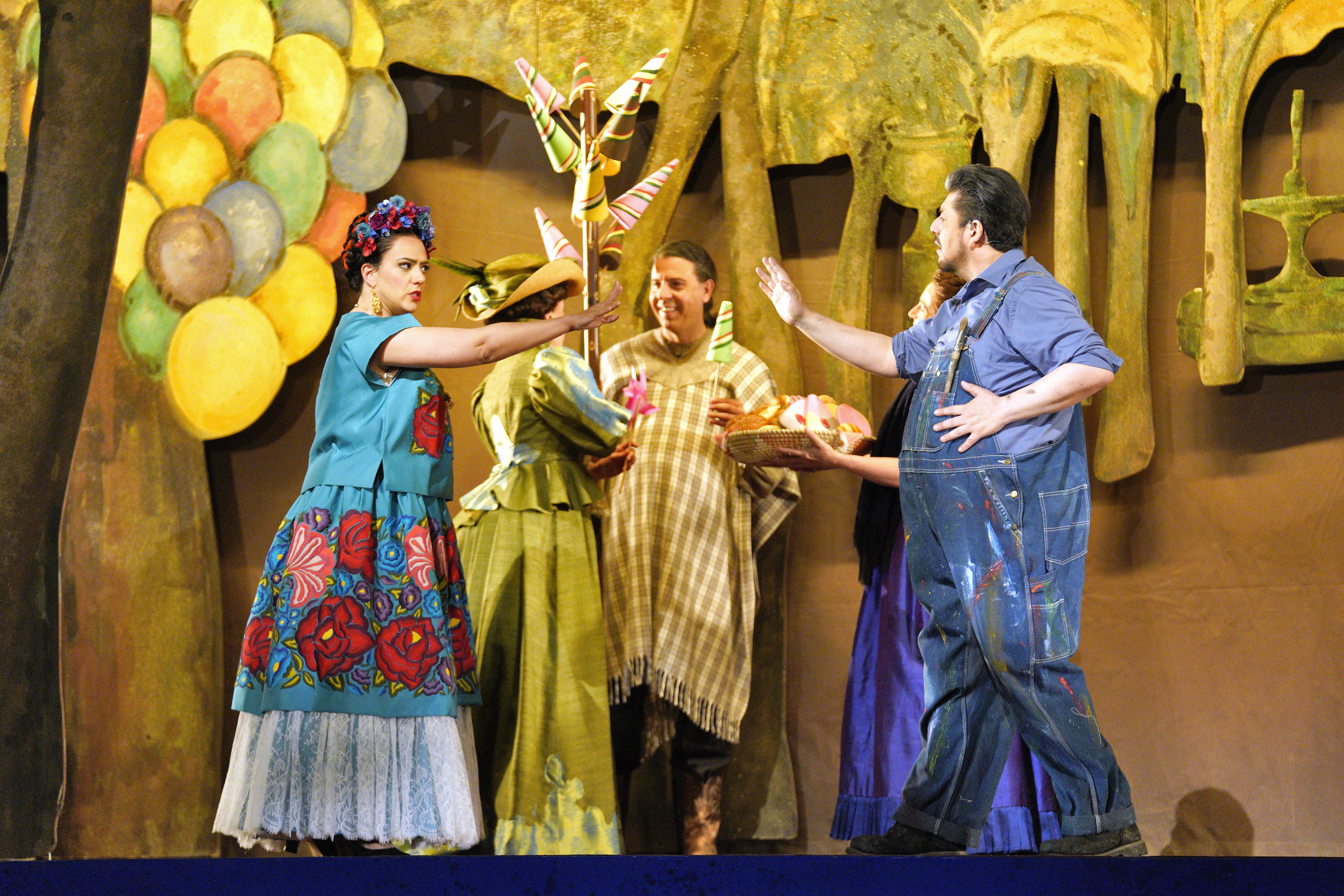 Scene from Frida of man in overalls reaching out to a woman in a colorful dress reaching out to him