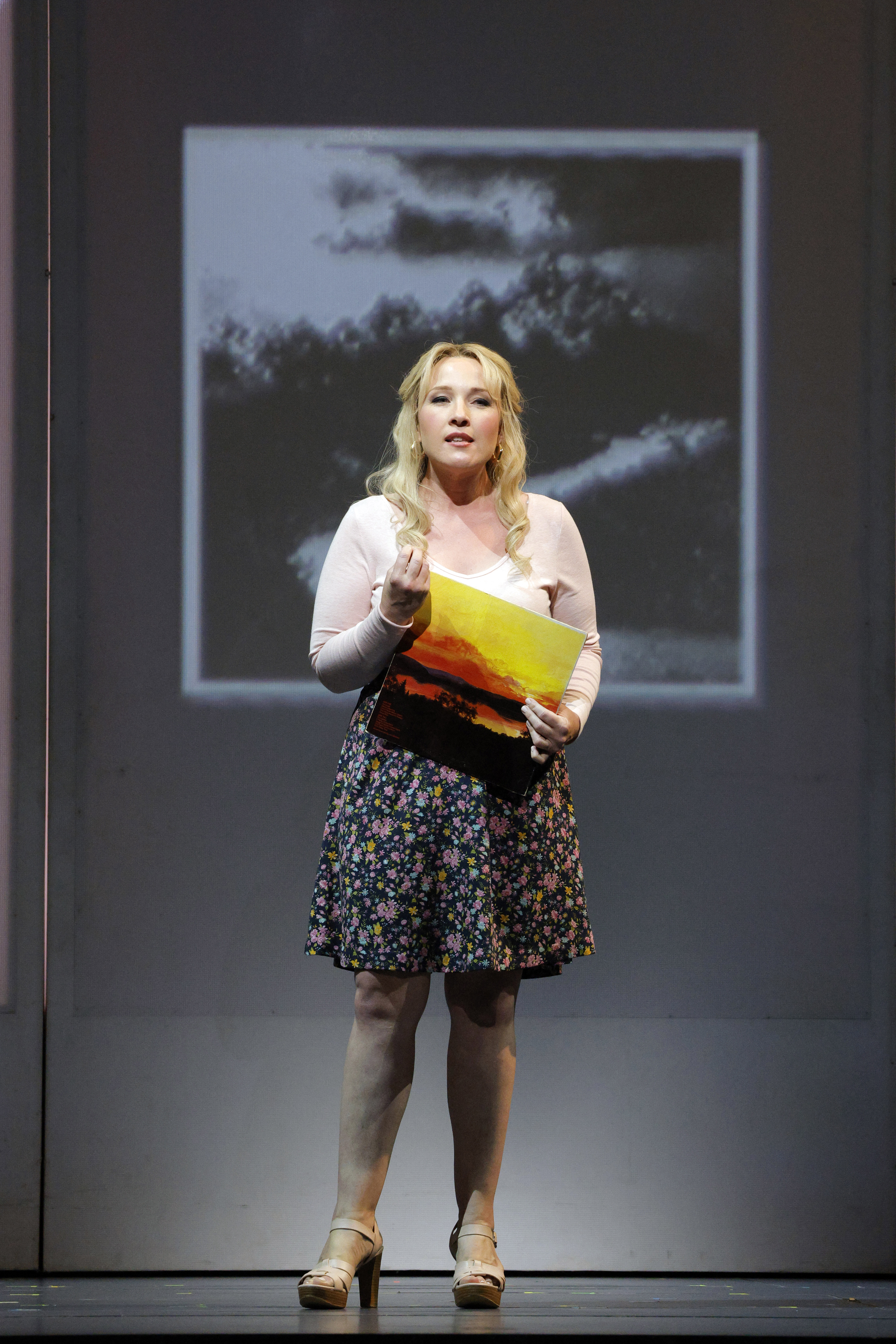 women holding picture standing on stage singing